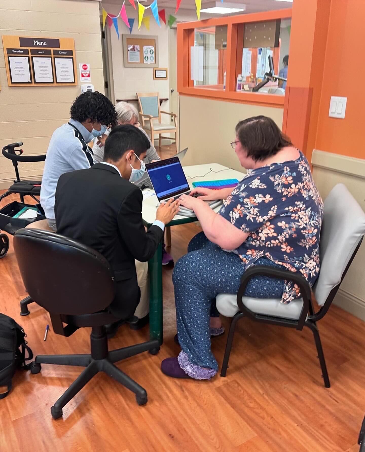 A TechWiseTutors volunteer helping a community member use a laptop